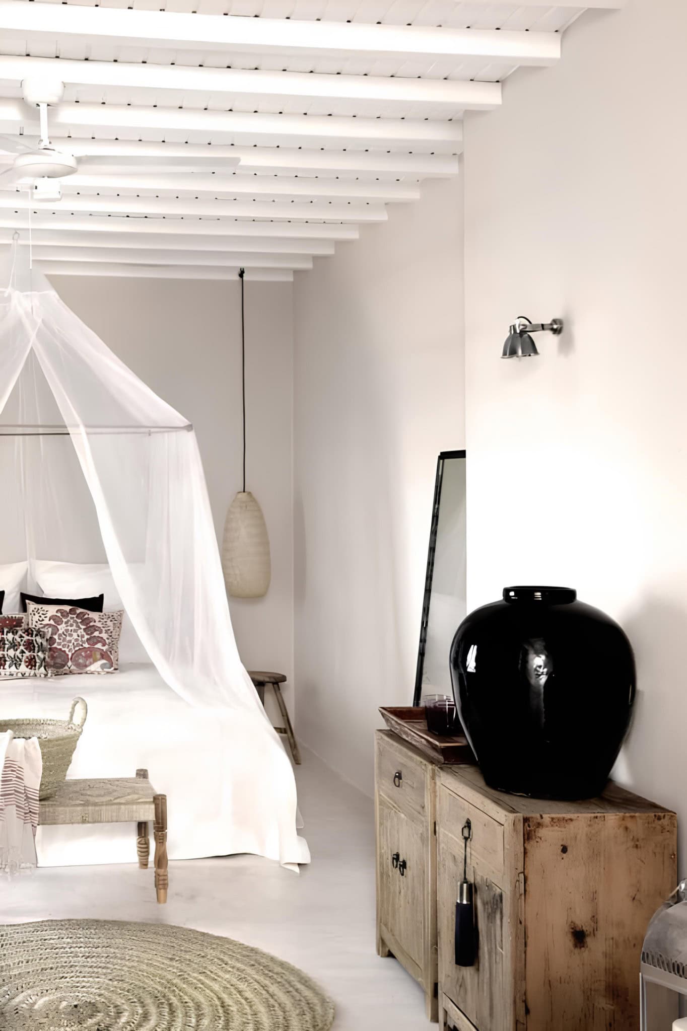 Neutral Bedroom Black Vase Decor Minimal bedroom with canopy bed, round rug, and black ceramic vase.