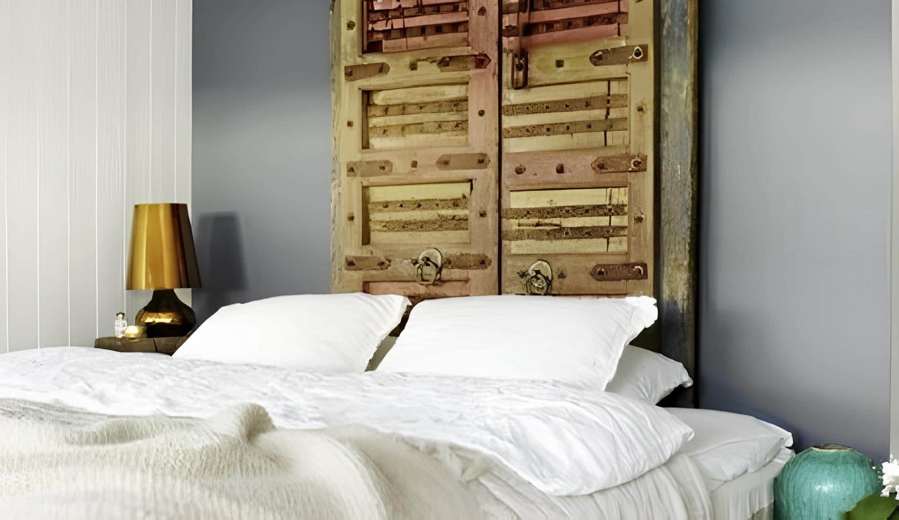 Vintage reclaimed wooden doors used as a unique headboard in a cozy bedroom