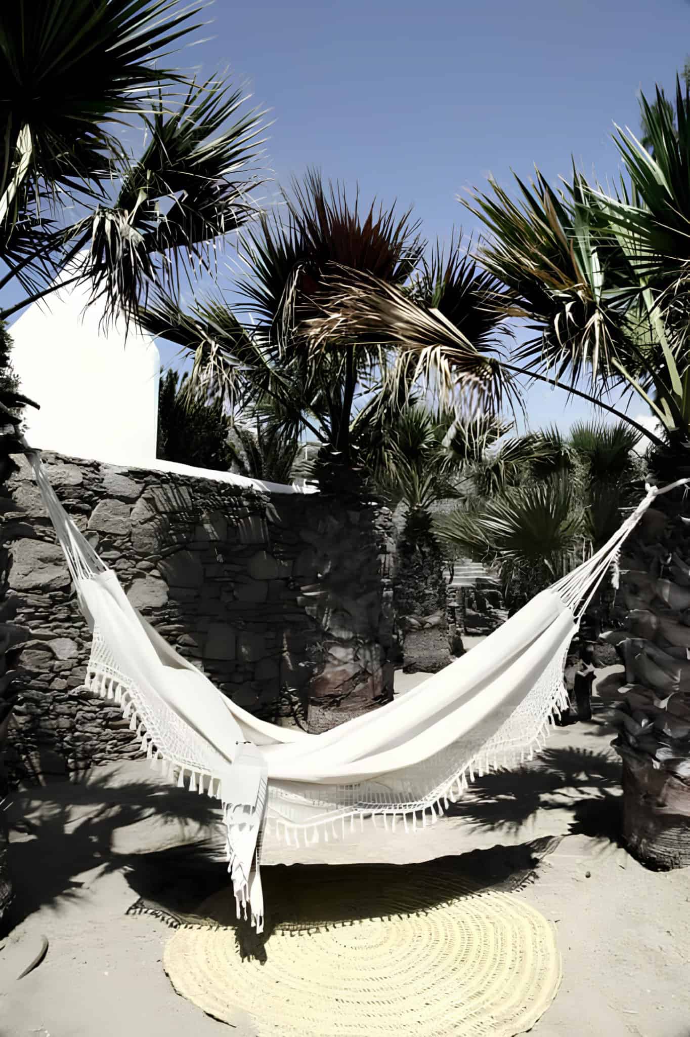 Stone Courtyard Hammock Palm Garden Relaxing white hammock under palm trees in a secluded stone courtyard.