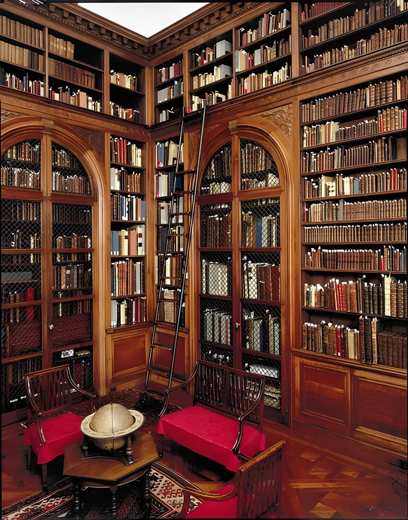 Traditional wood-paneled library with rolling ladder and red upholstered chairs