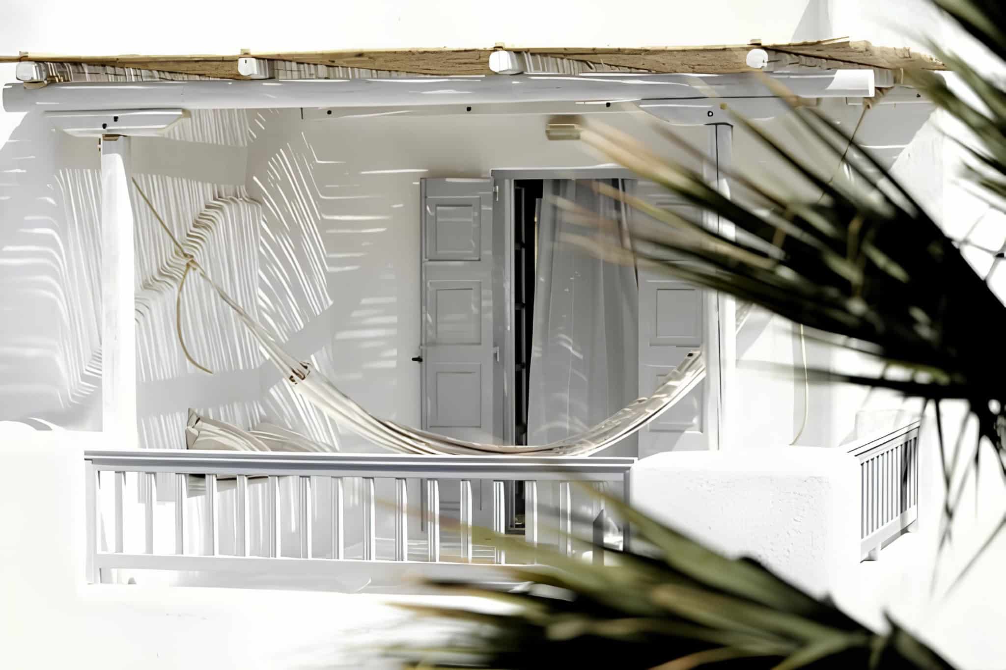 White Balcony Hammock Palm Shadow Bright balcony with white hammock and dramatic palm shadows on the wall.
