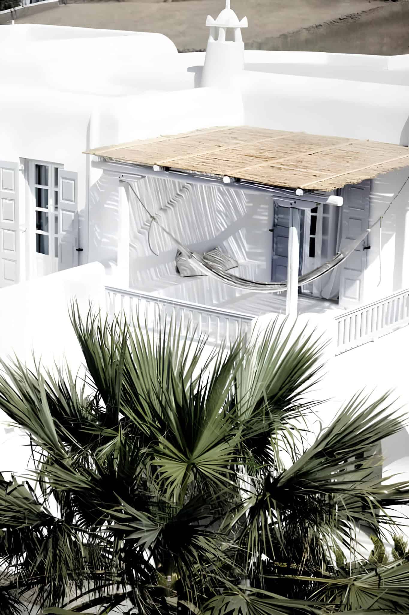 White Balcony Hammock Palm Shadows Sunlit white balcony with hammock and palm shadows on the wall.