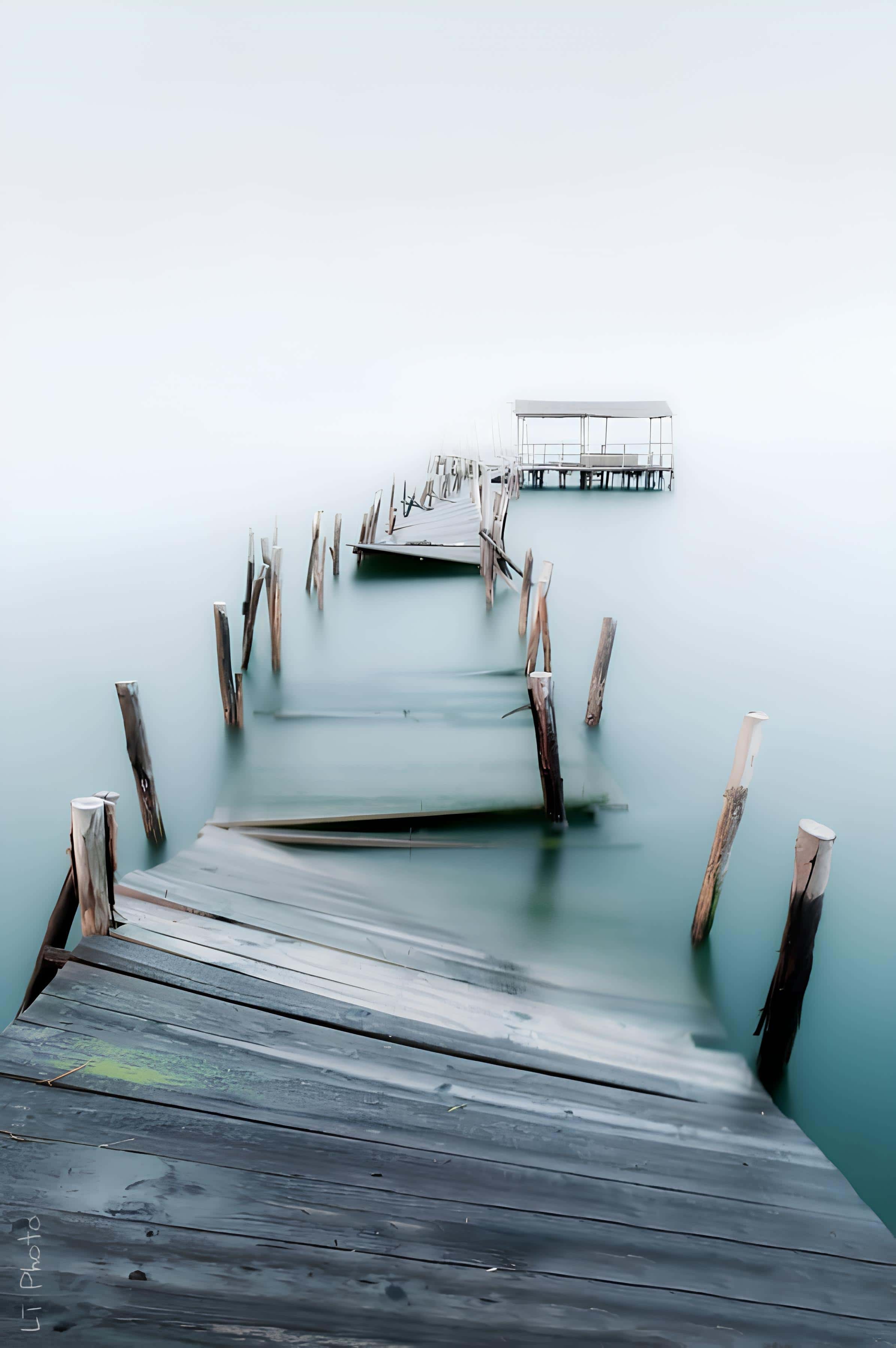 Abandoned Dock Over Misty Lake Broken wooden dock fading into mist over calm water