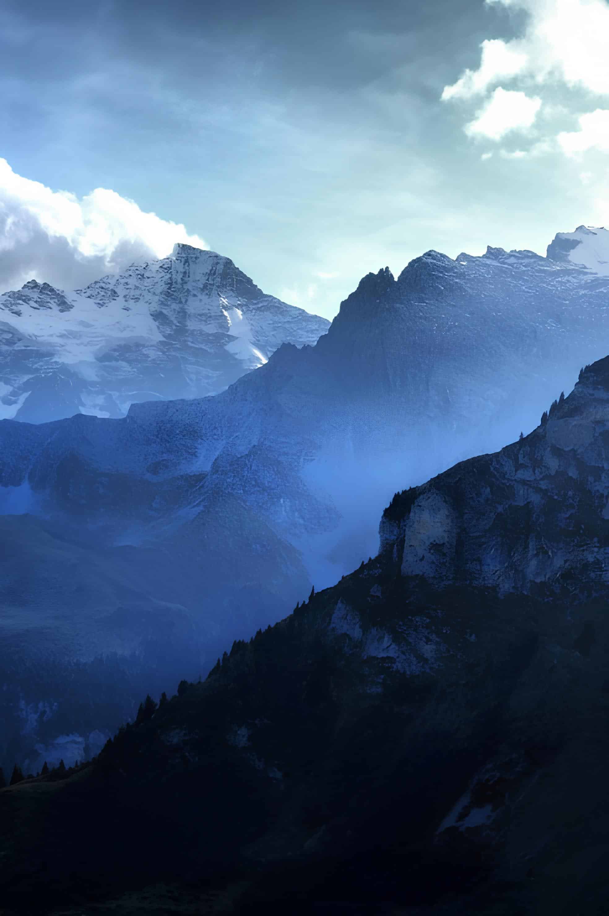 Blue-Hued Alpine Mountainscape Layered mountain ridges under dramatic sky in blue tones