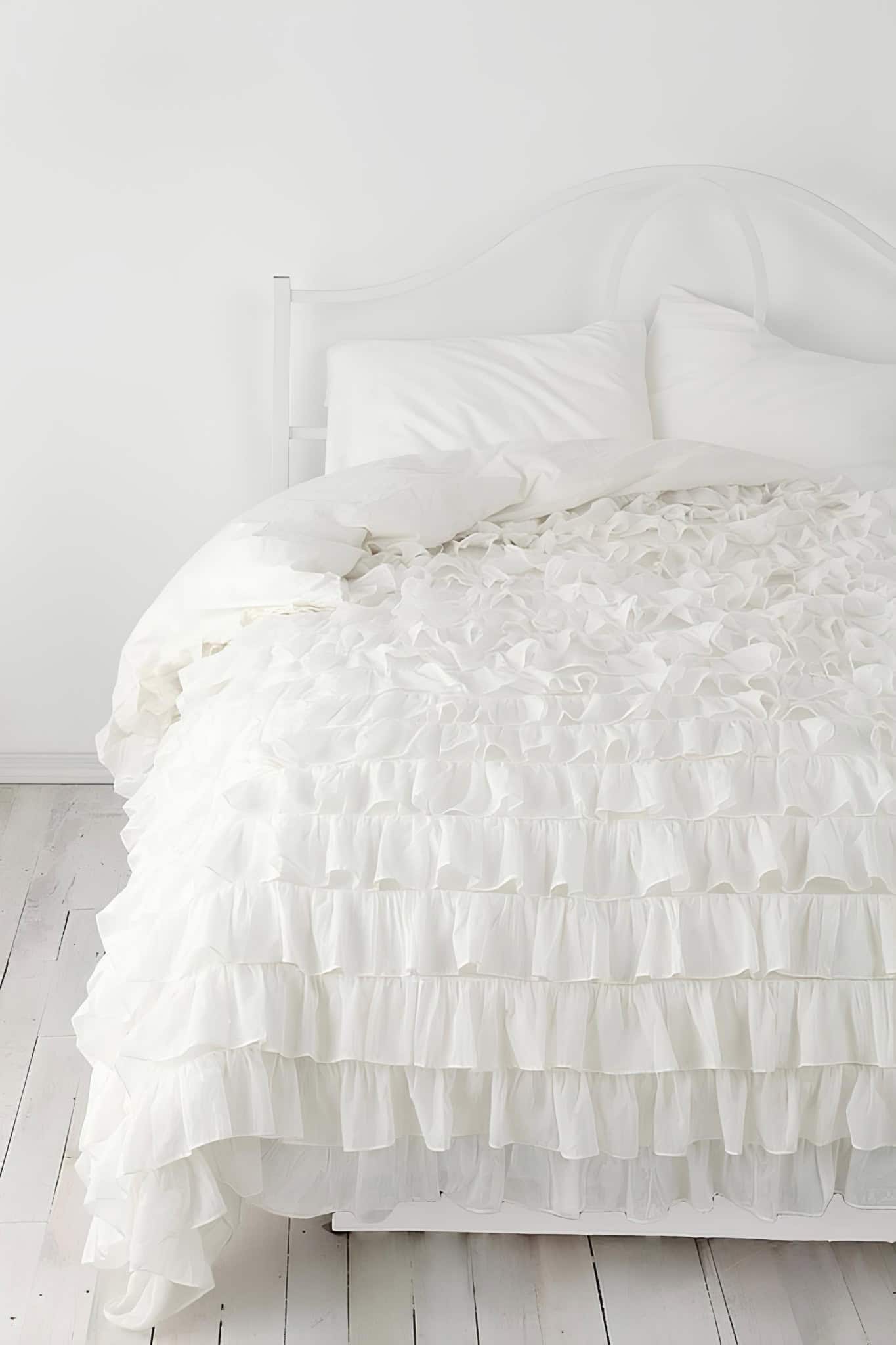 Cottage Style Bedroom with Tiered Ruffle Bedding White cottage-style bedroom with tiered ruffle bedding on whitewashed floor