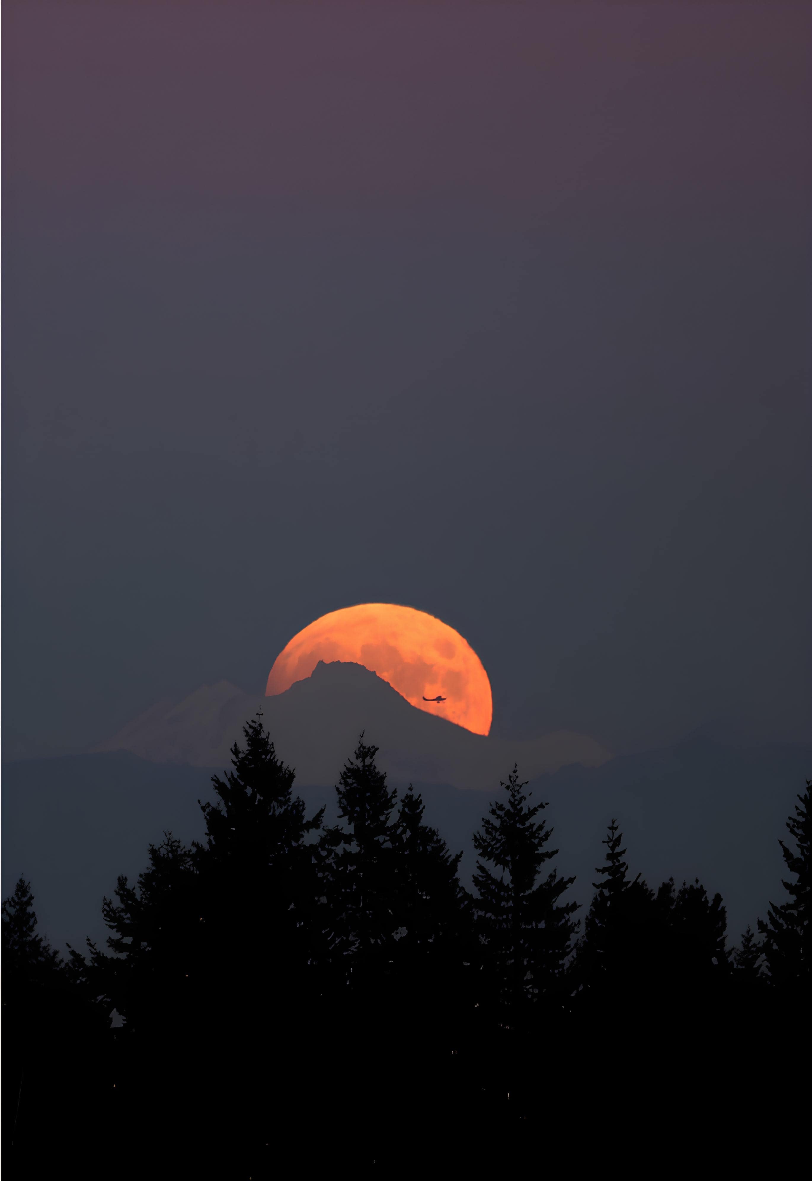 Moonrise Behind Mountain Peaks Full moon rising over silhouette of mountain ridge