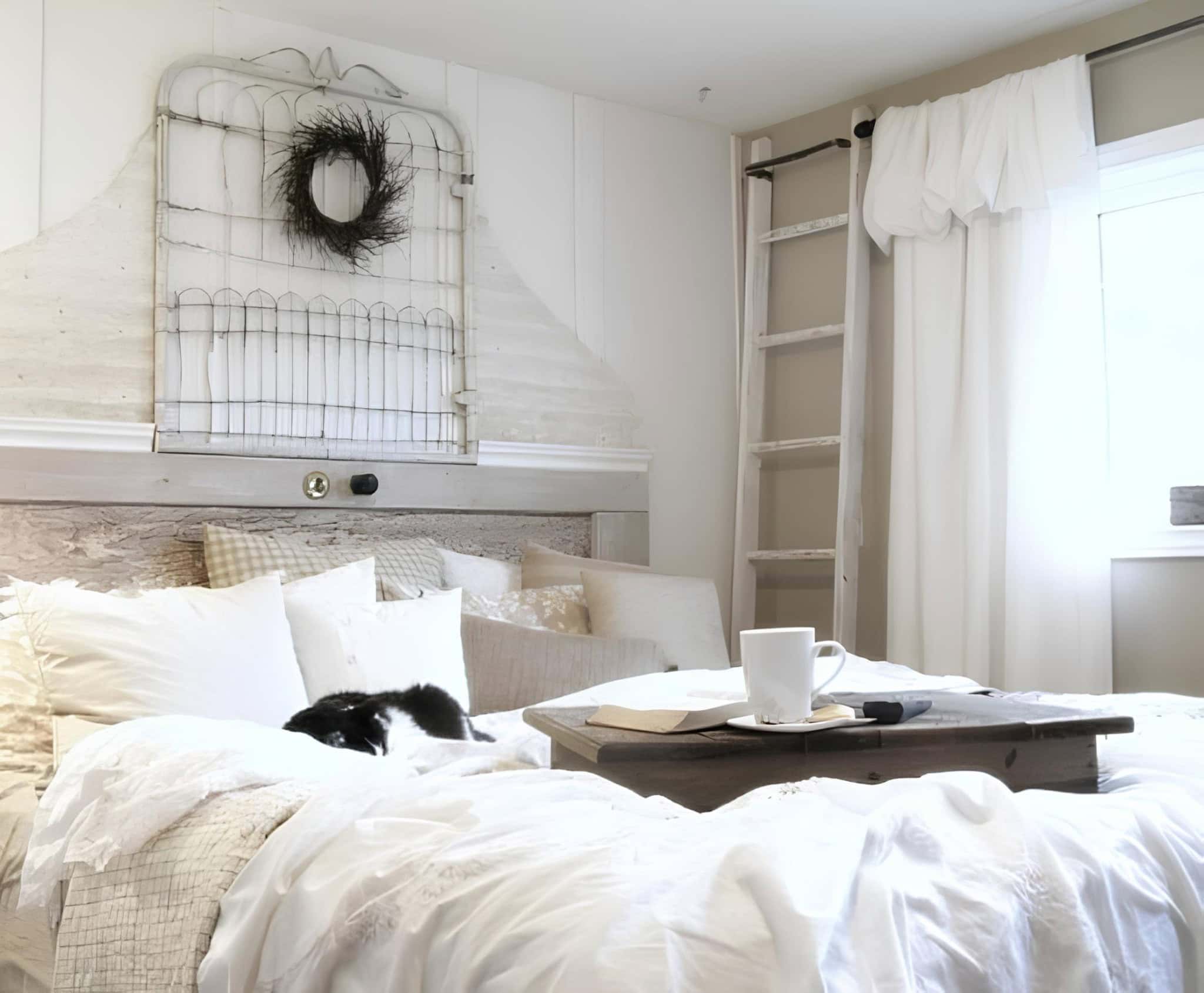 Rustic White Bedroom with Cat and Wrought Iron Wall Decor Rustic white bedroom with a black cat on the bed and wreath on iron headboard