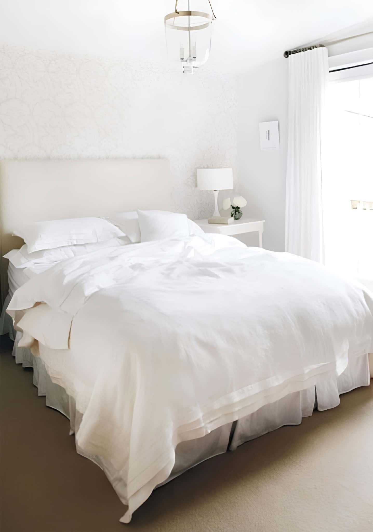 Serene White Bedroom with Upholstered Headboard Neutral bedroom with white bedding, soft headboard, and modern lamp
