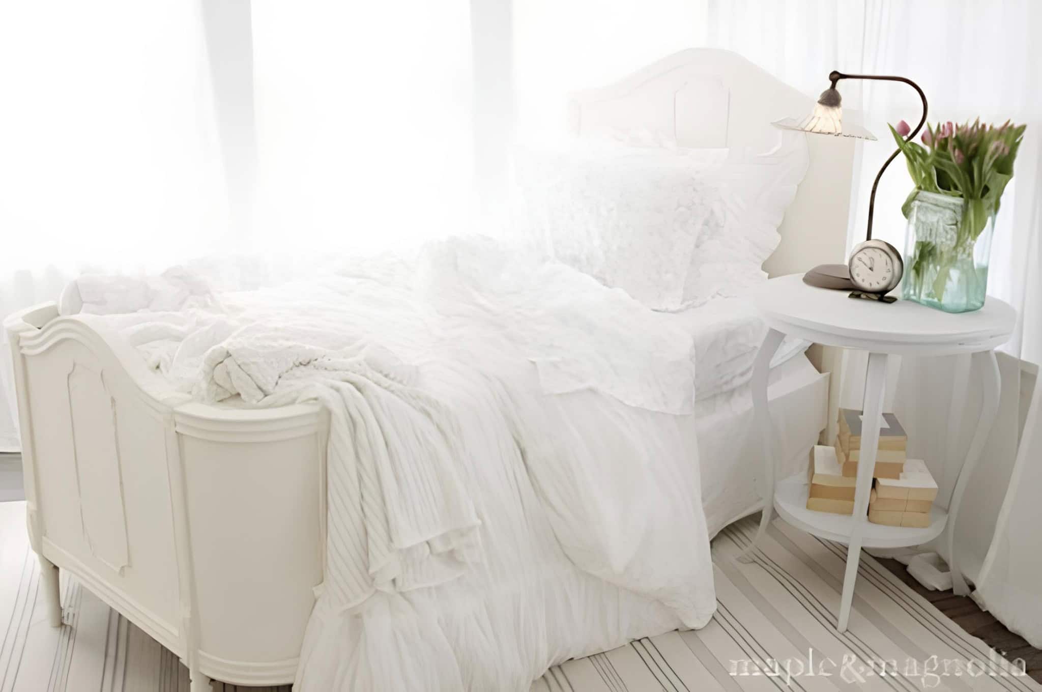 Shabby Chic White Bedroom with Vintage Bed All-white shabby chic bedroom with ornate bed, striped rug, and tulips in vase