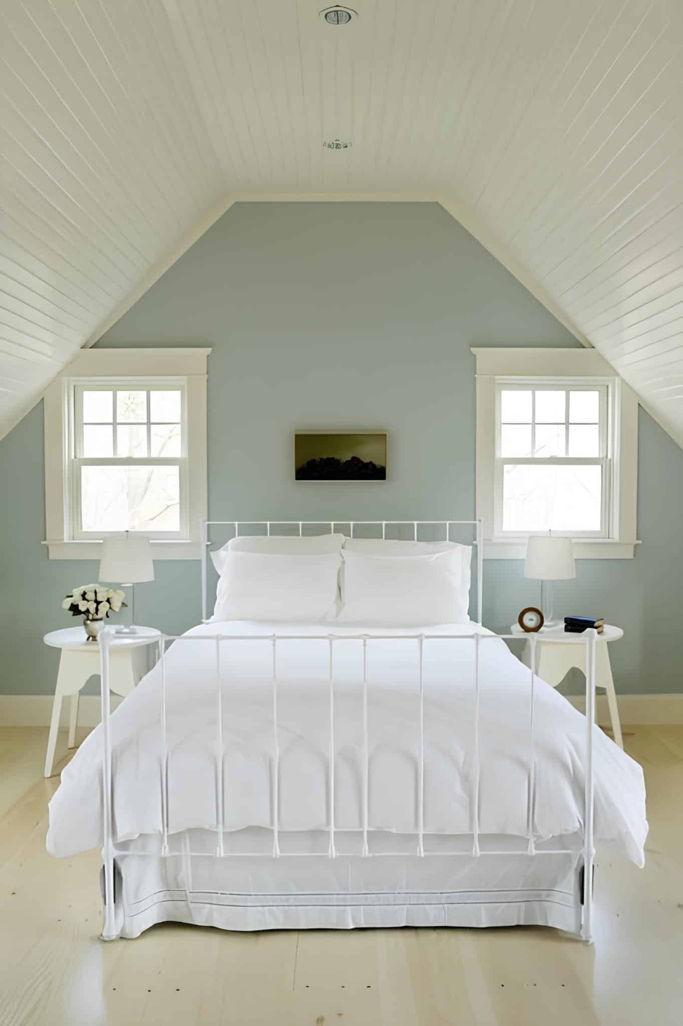 Cozy attic bedroom with white bed and pastel blue walls