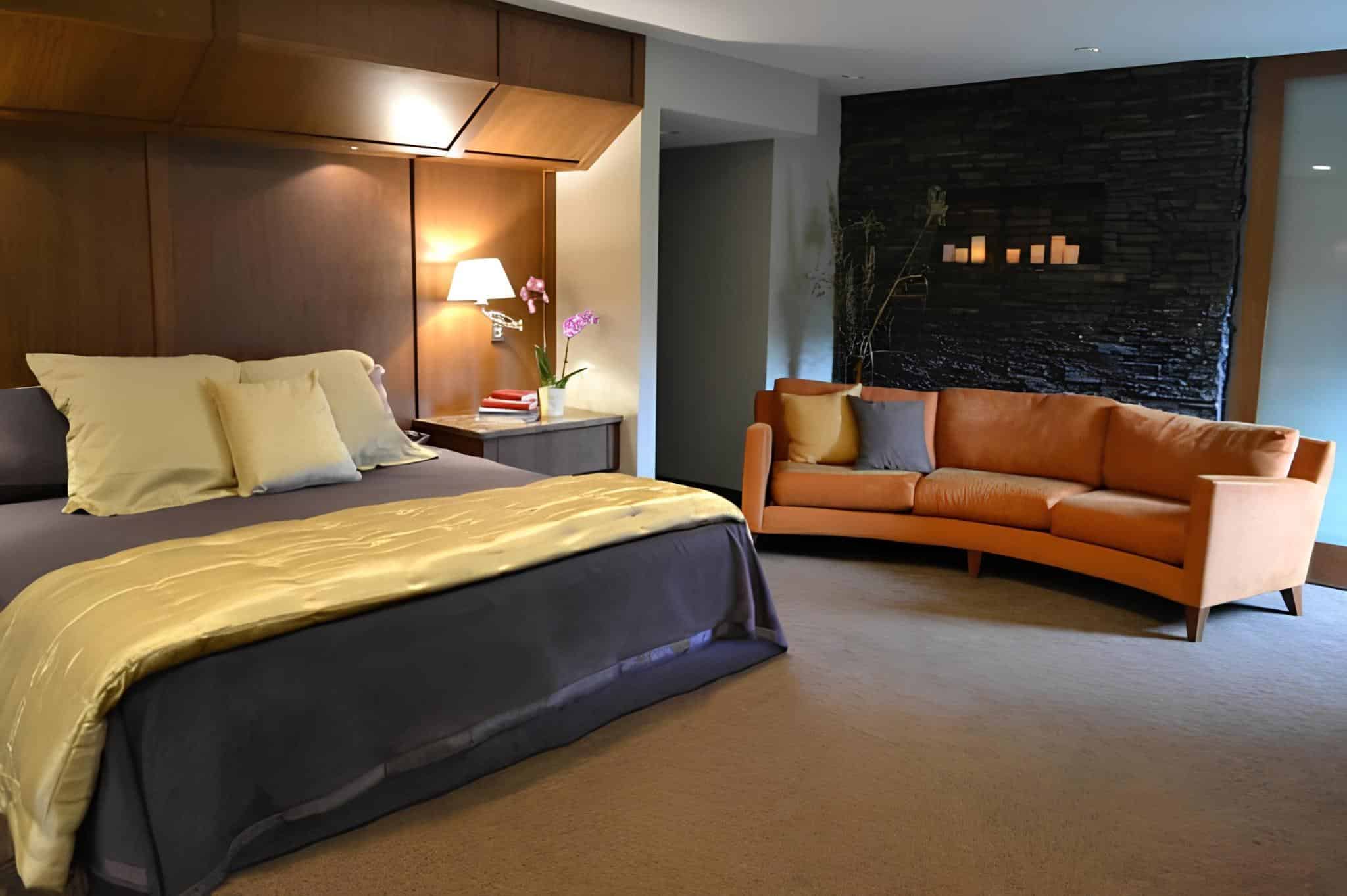 Bedroom with orange sofa, dark accent wall, and warm lighting