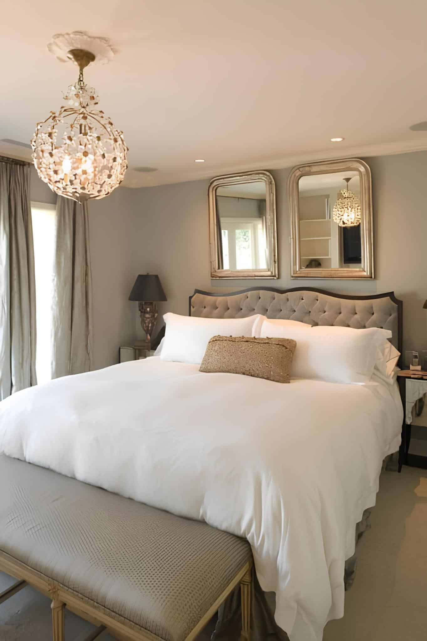Elegant bedroom with a tufted headboard, white bedding, and a crystal chandelier
