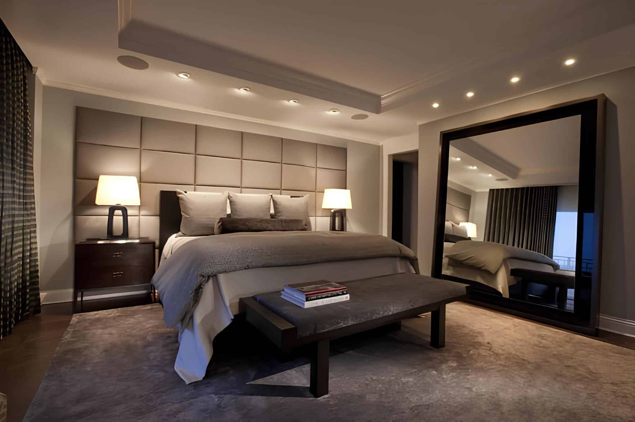 Upscale bedroom with padded headboard, large mirror, and modern spotlights