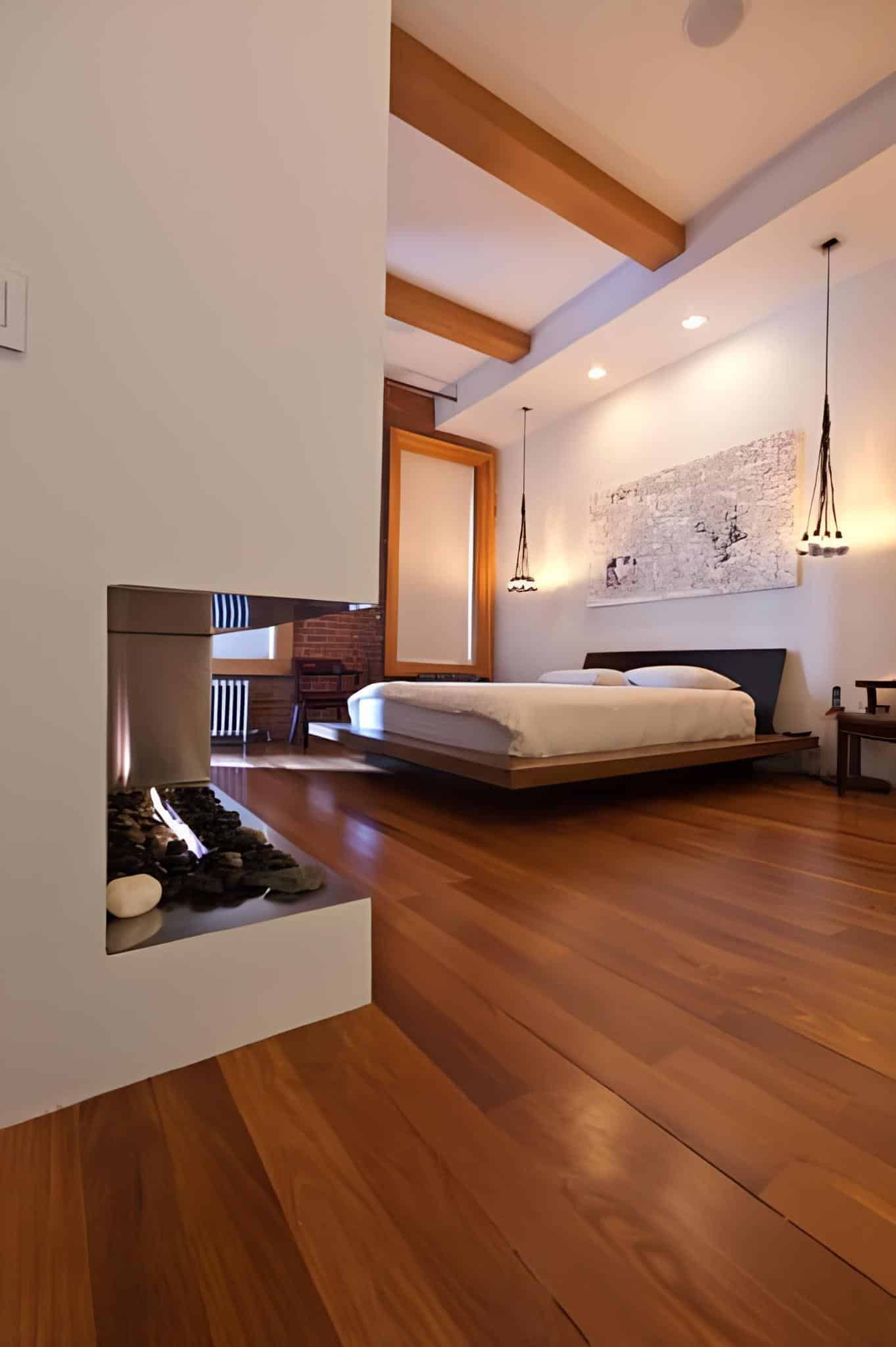 Modern bedroom with wood floors and suspended gas fireplace