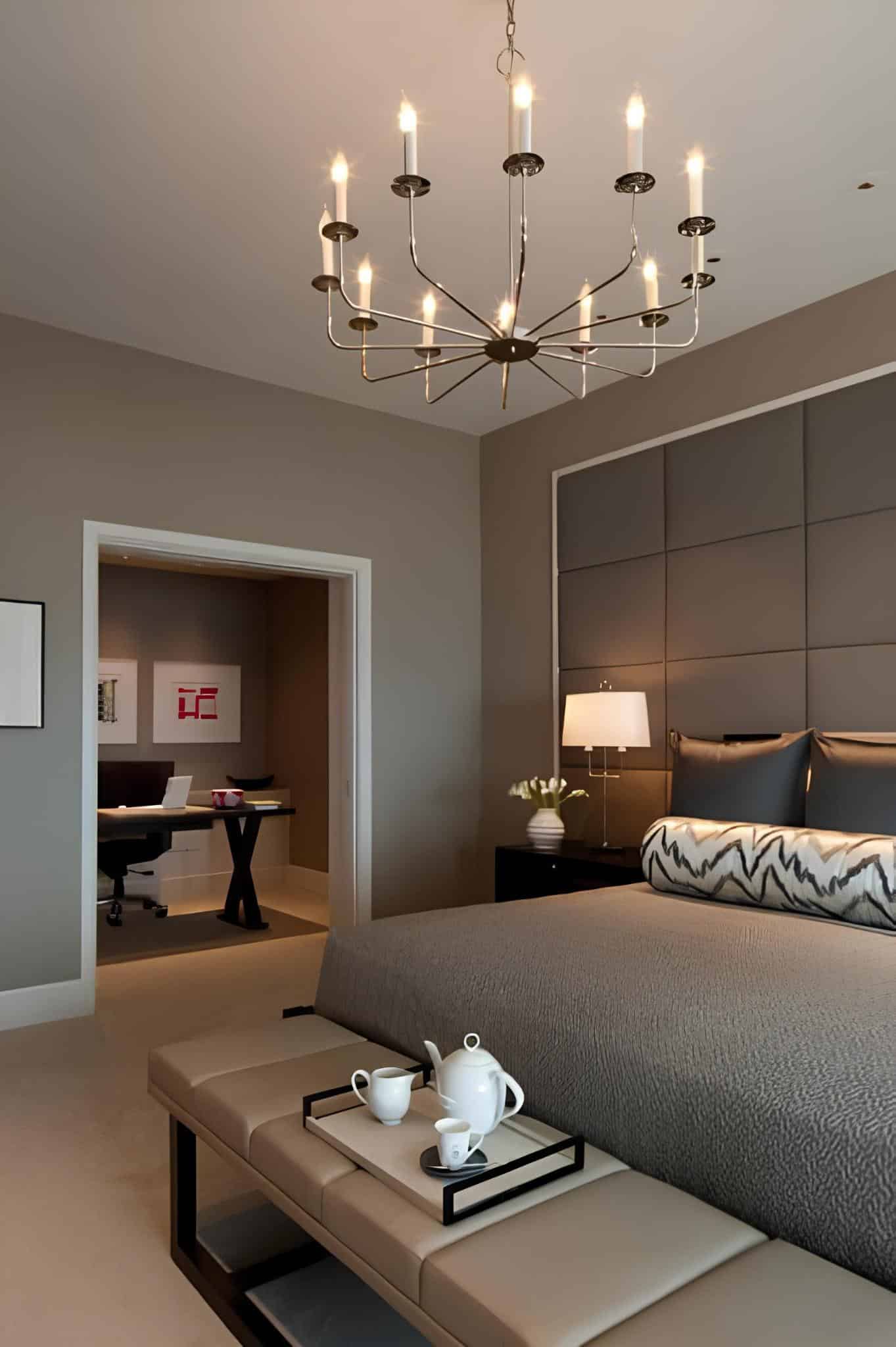 Neutral-toned bedroom with matching bench, elegant lighting, and office nook