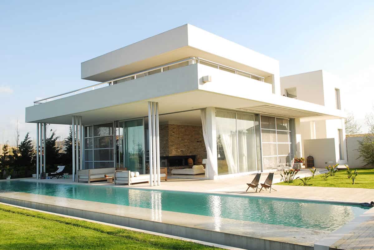 Modern luxury architectural design of a contemporary white house with large glass windows, outdoor pool, and sleek minimalist style.