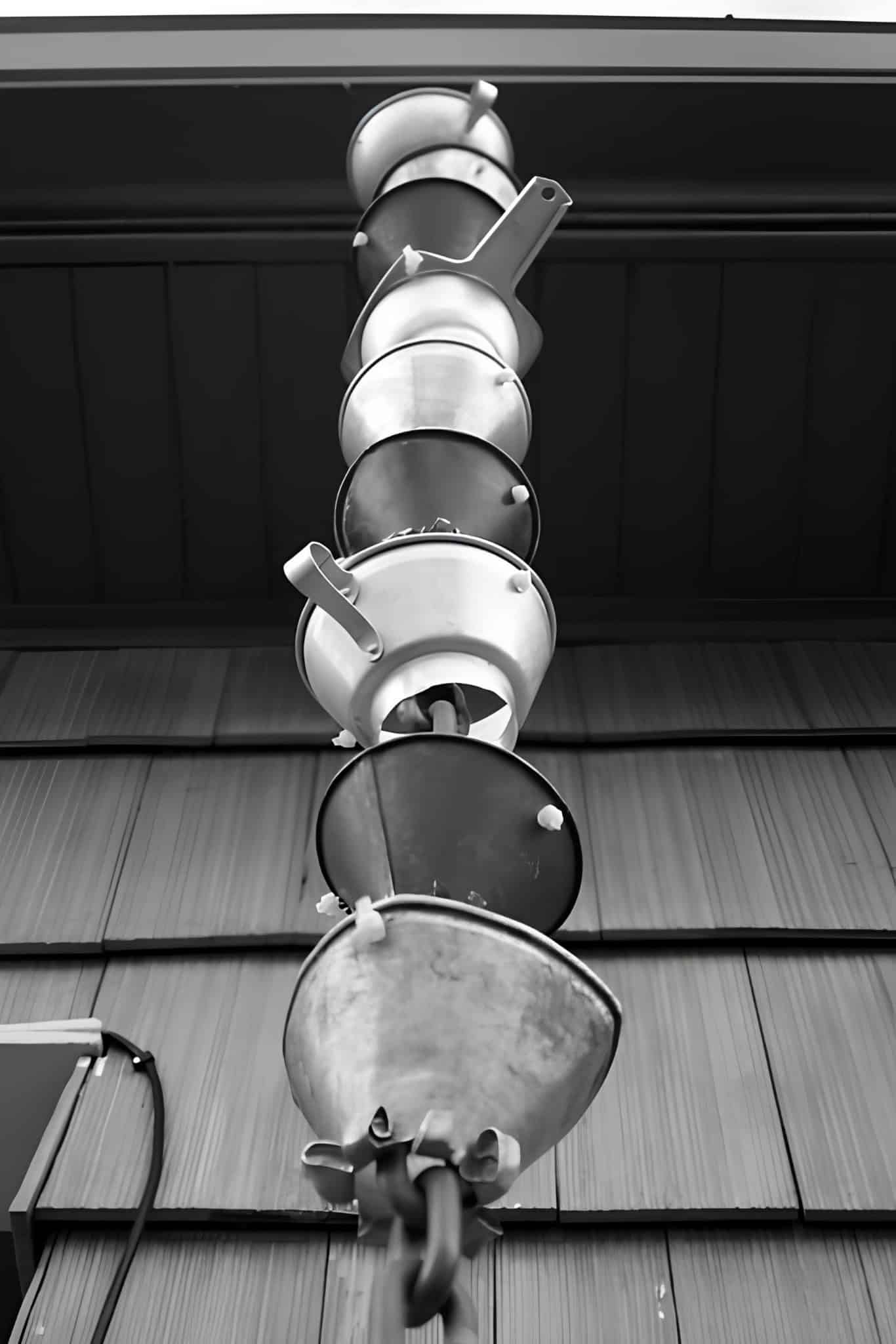 DIY rain chain made from stacked galvanized funnels against metal siding