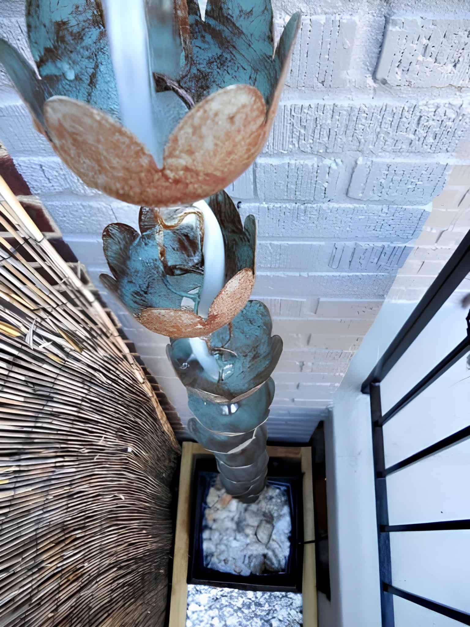 Rain chain made from rustic blue cups channeling water down a building corner