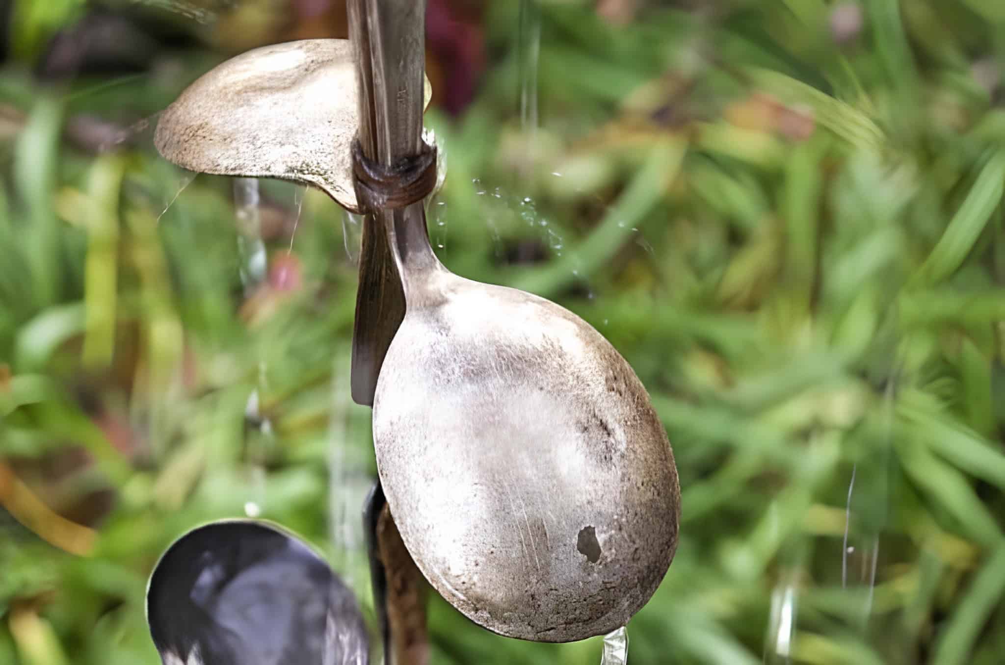 Close-up of a vintage metal spoon rain chain with water flowing over it