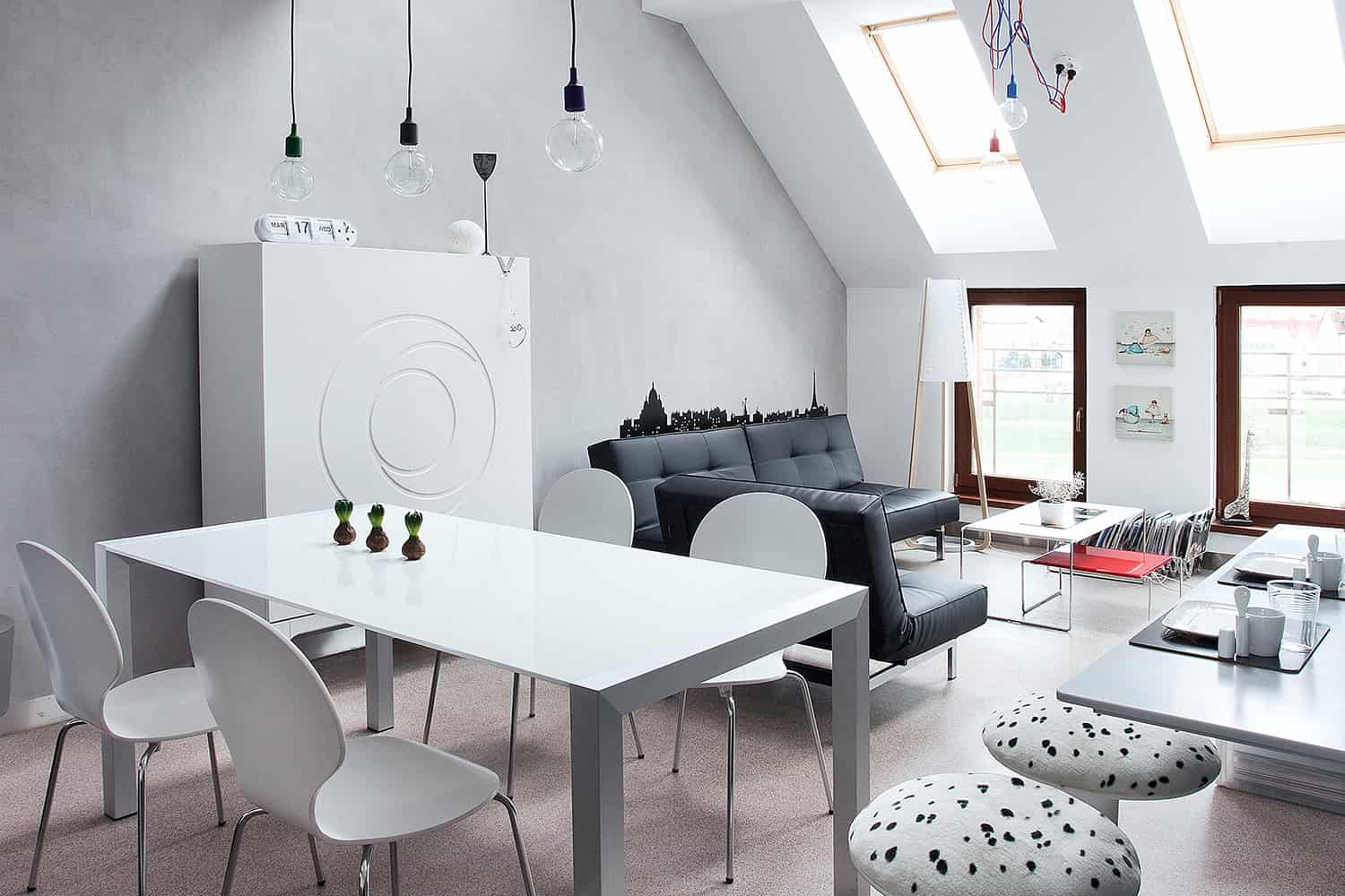 Contemporary attic living room with modern furniture, skylights, and minimalist decor, featuring black and white color scheme and stylish natural light design.
