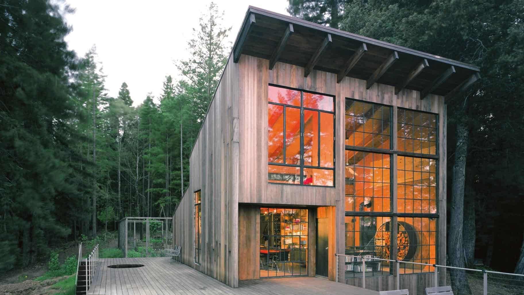 Modern wooden house with large glass windows, nestled in lush forest surroundings, showcasing contemporary architecture and eco-friendly design for nature integration.