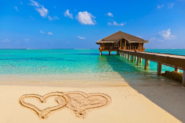 Drawing connected hearts on beach - concept holiday background