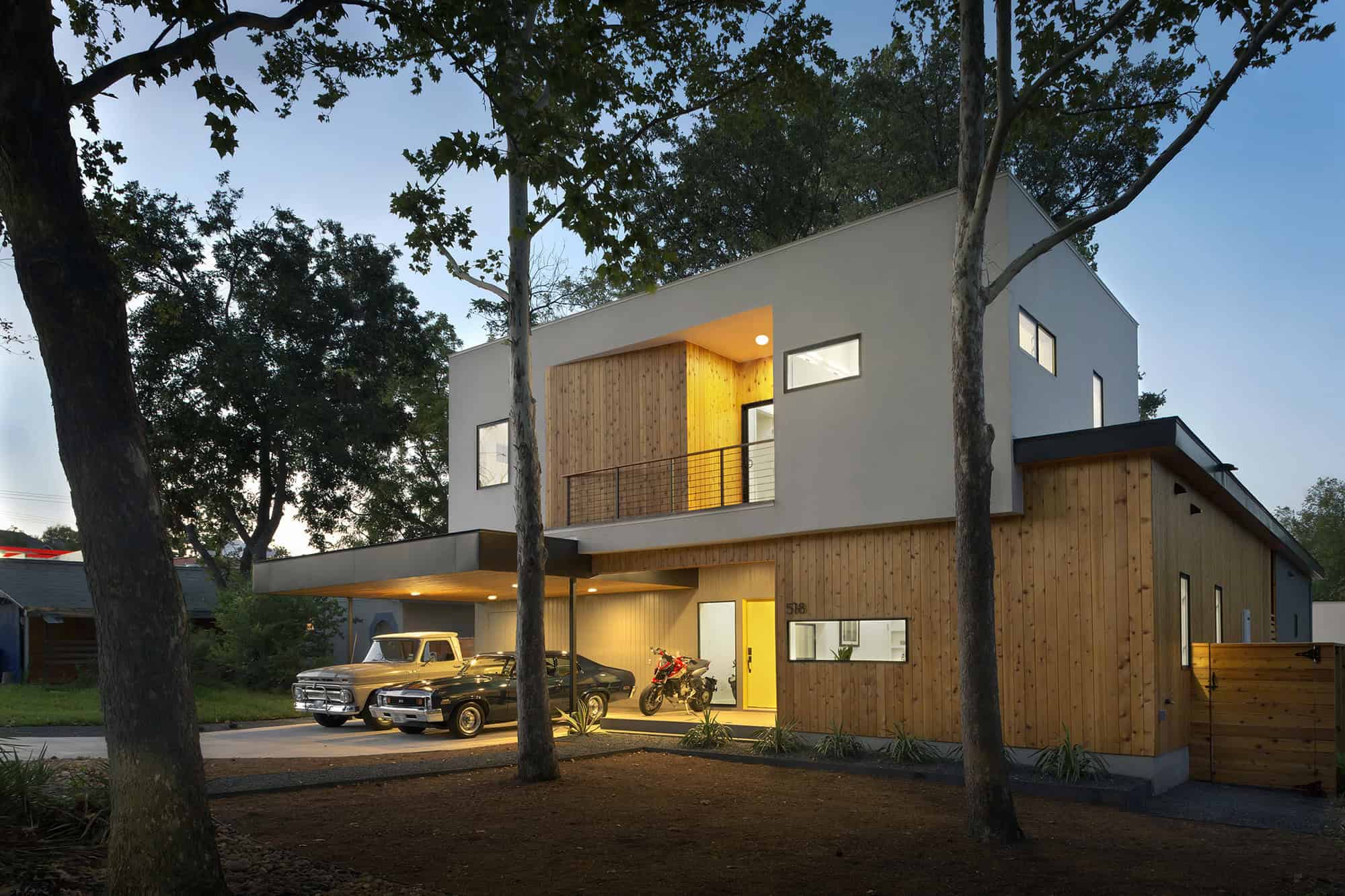 Contemporary modern house with a minimalist design, mixed wood and stucco exterior, large windows, and a spacious carport, surrounded by trees for a natural aesthetic and sustainable architecture appeal.