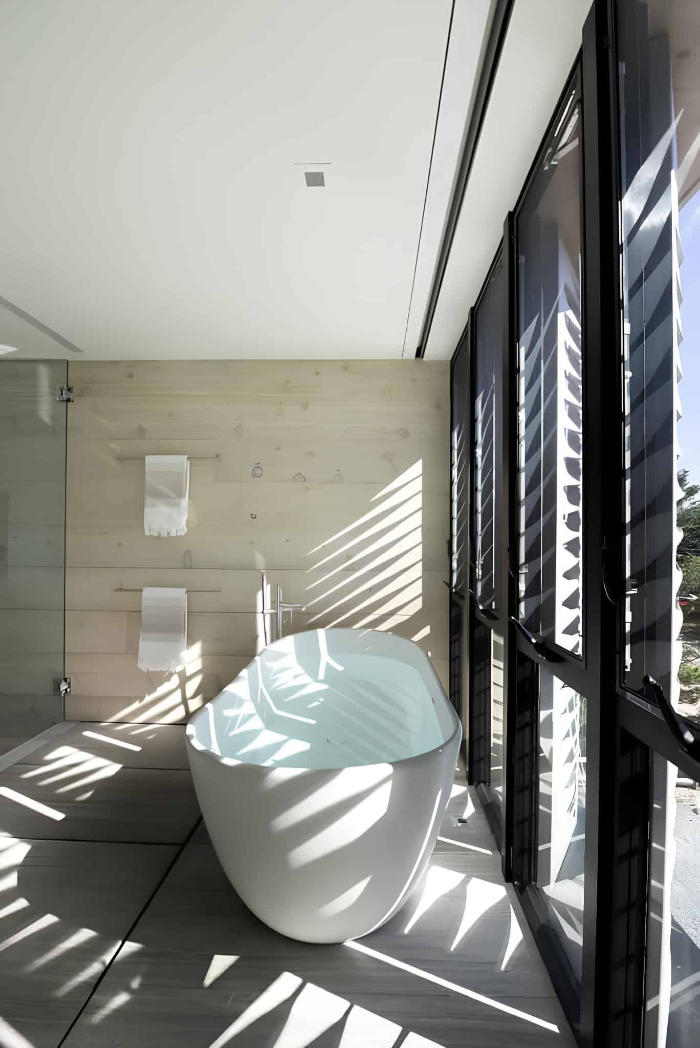 Freestanding Tub Light Patterns Bathroom Freestanding tub with sunlight patterns in modern bathroom.