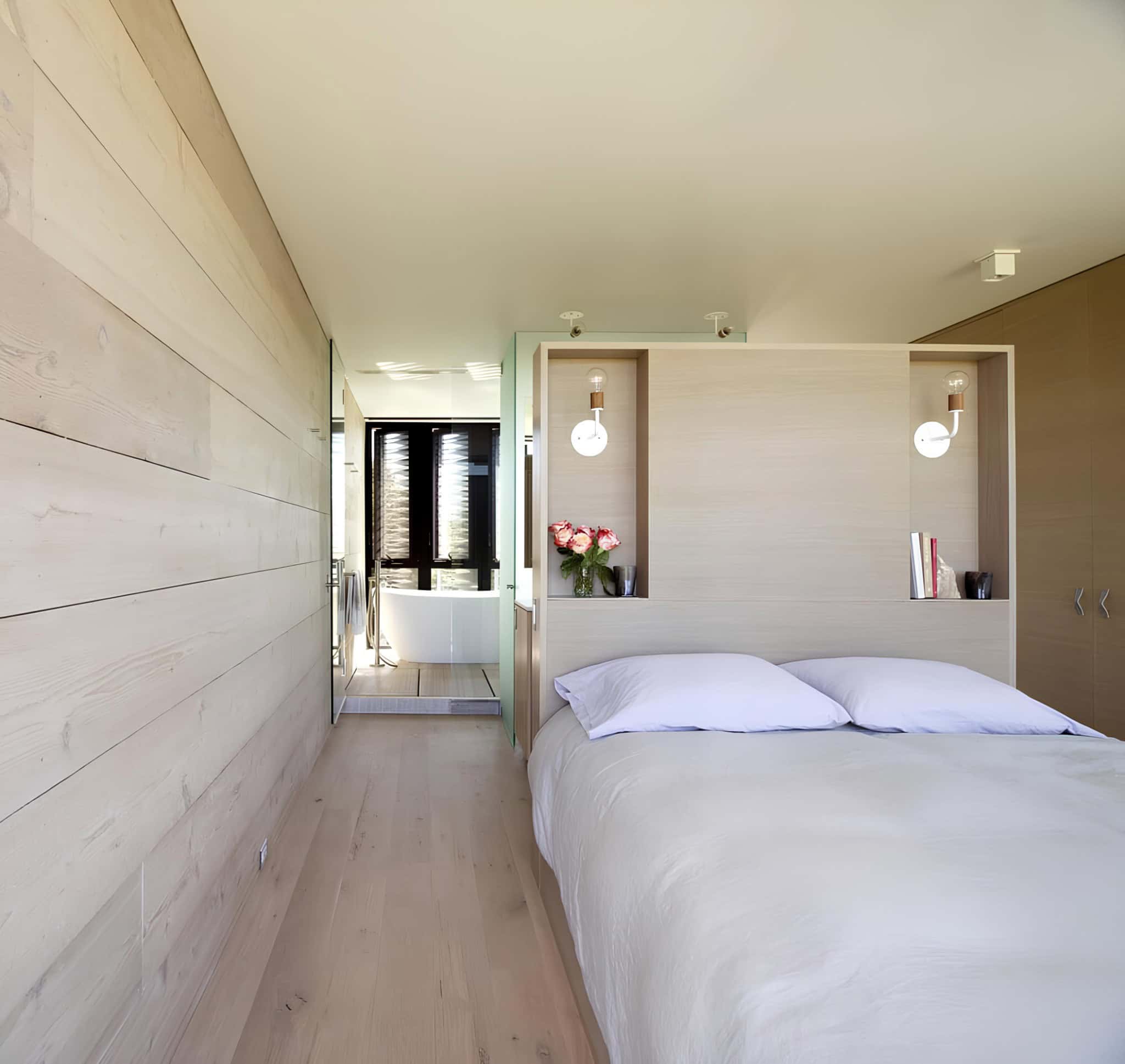 Minimalist Bedroom Light Wood Paneling Minimalist bedroom with light wood walls and integrated bathroom view.