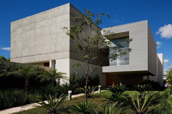 Contemporary modern house with minimalist architecture, concrete walls, large windows, and lush landscaping, showcasing innovative design and clean geometric lines.