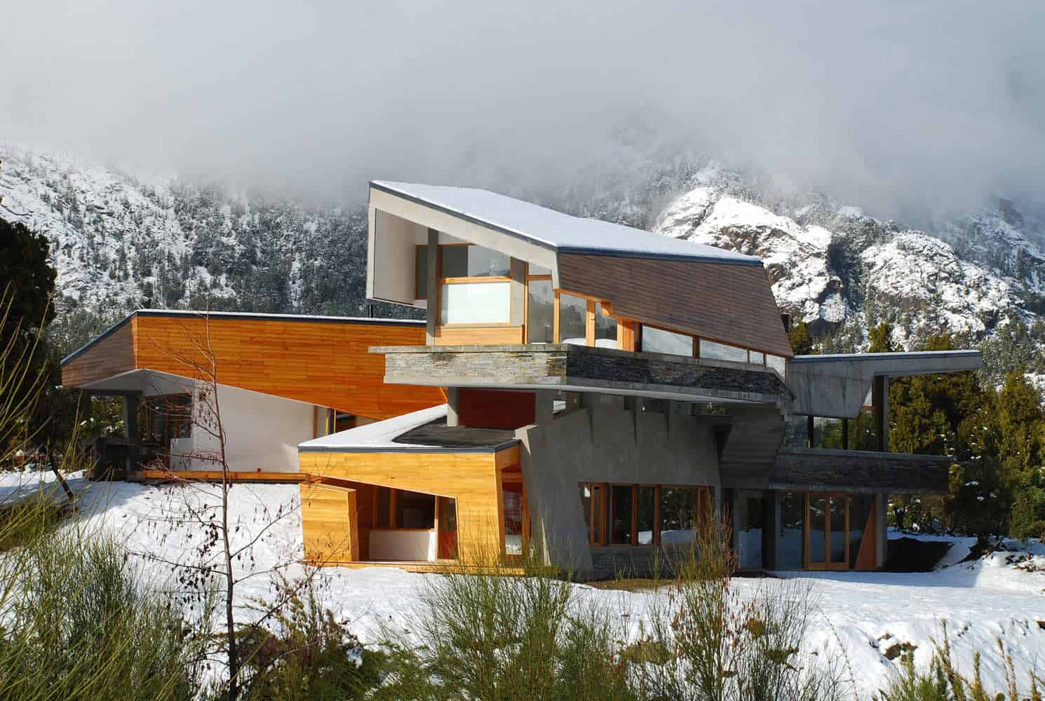 Contemporary mountain house with modern architectural design, large windows, and mixed materials in a snowy landscape, highlighting innovative architecture art and modern residential design.