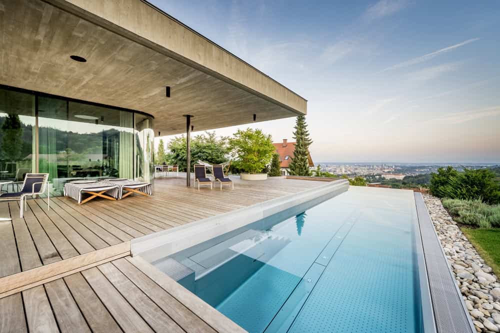 Modern luxury home with infinity pool and spacious outdoor patio overlooking scenic landscape, blending contemporary architecture with outdoor living design.