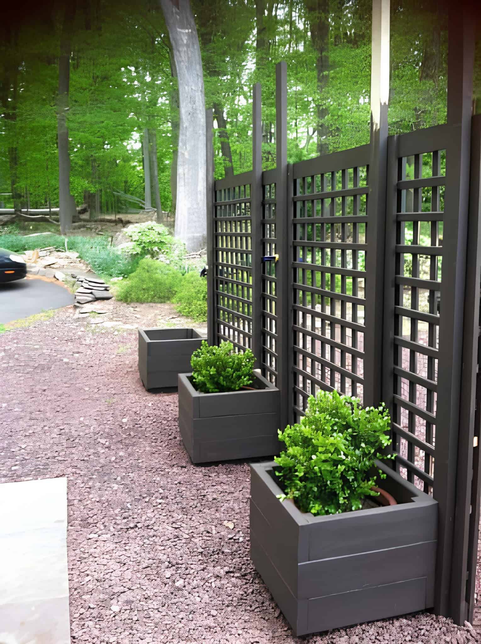 Modern black lattice fence with planters along a gravel garden path