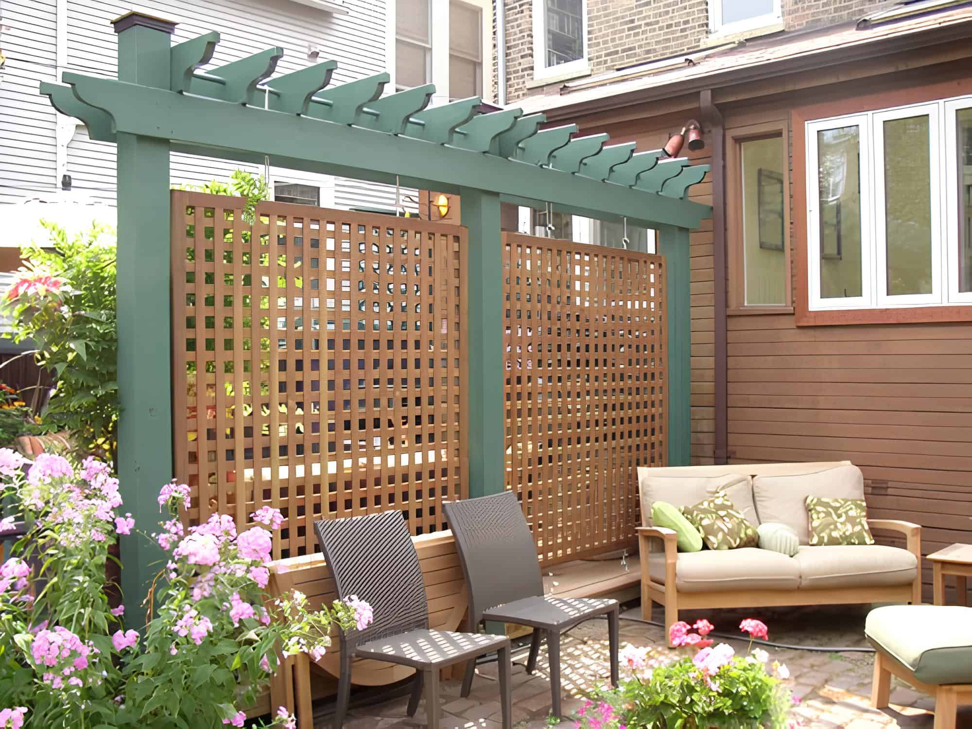 Wooden lattice screen under a painted green pergola in a cozy backyard