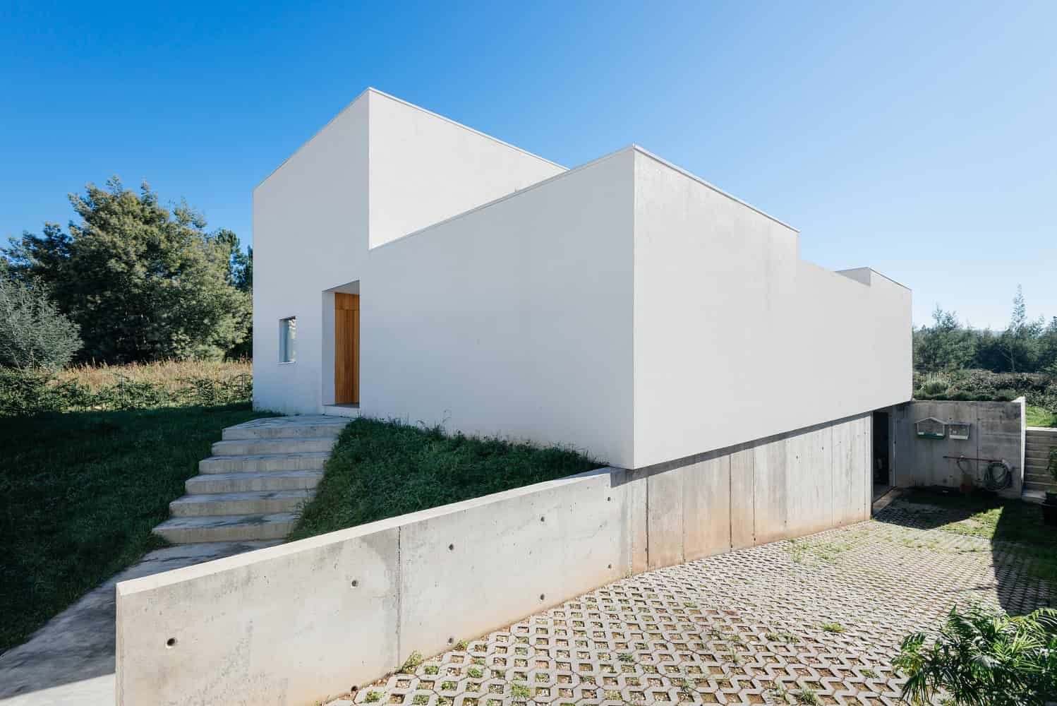 Contemporary minimalist white house with clean geometric lines, modern architecture, and unique cubic design. Perfect example of sleek, modern residential architecture with outdoor stairs and landscaped surroundings.
