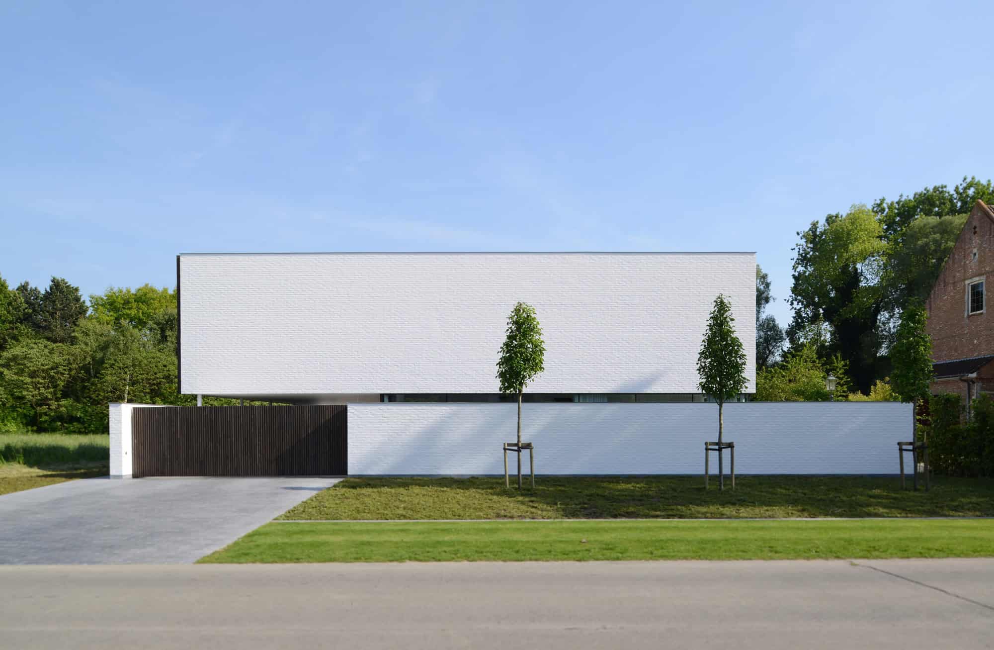 Sleek modern minimalist house with white brick facade, clean lines, and landscaped yard, showcasing contemporary architecture and innovative design.