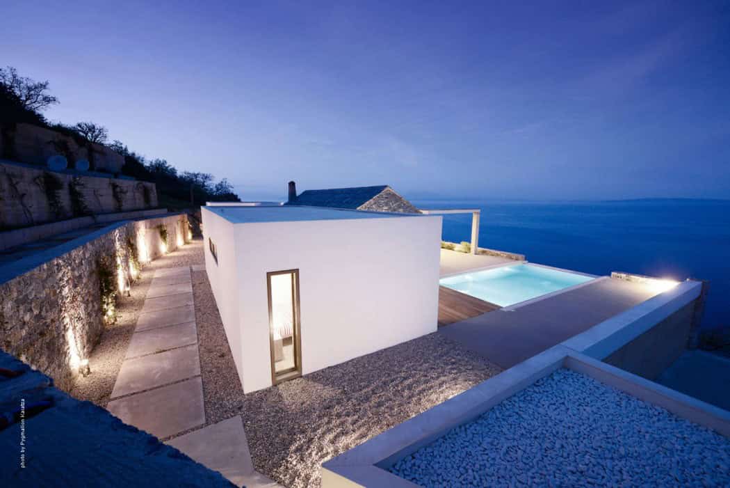 Modern minimalist house with infinity pool overlooking the sea, innovative architecture design, and elegant outdoor lighting, situated on a coastal cliff for luxury seaside living.