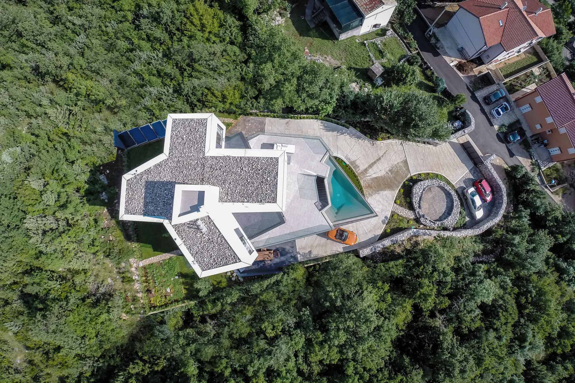 Modern contemporary house with swimming pool, aerial view of luxurious residential property, surrounded by lush greenery and landscaped gardens, blending modern architecture with nature.