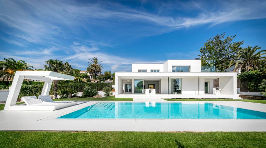 Modern white luxury house with sleek design, outdoor swimming pool, and tropical landscaping, showcasing contemporary architecture and stylish outdoor living spaces.