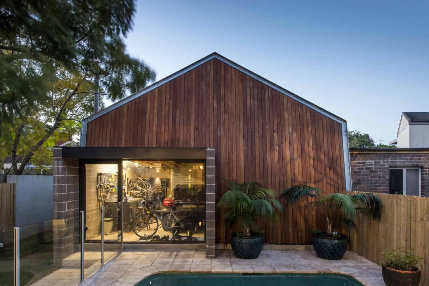 Modern wooden garage with glass doors and outdoor pool in contemporary backyard.
