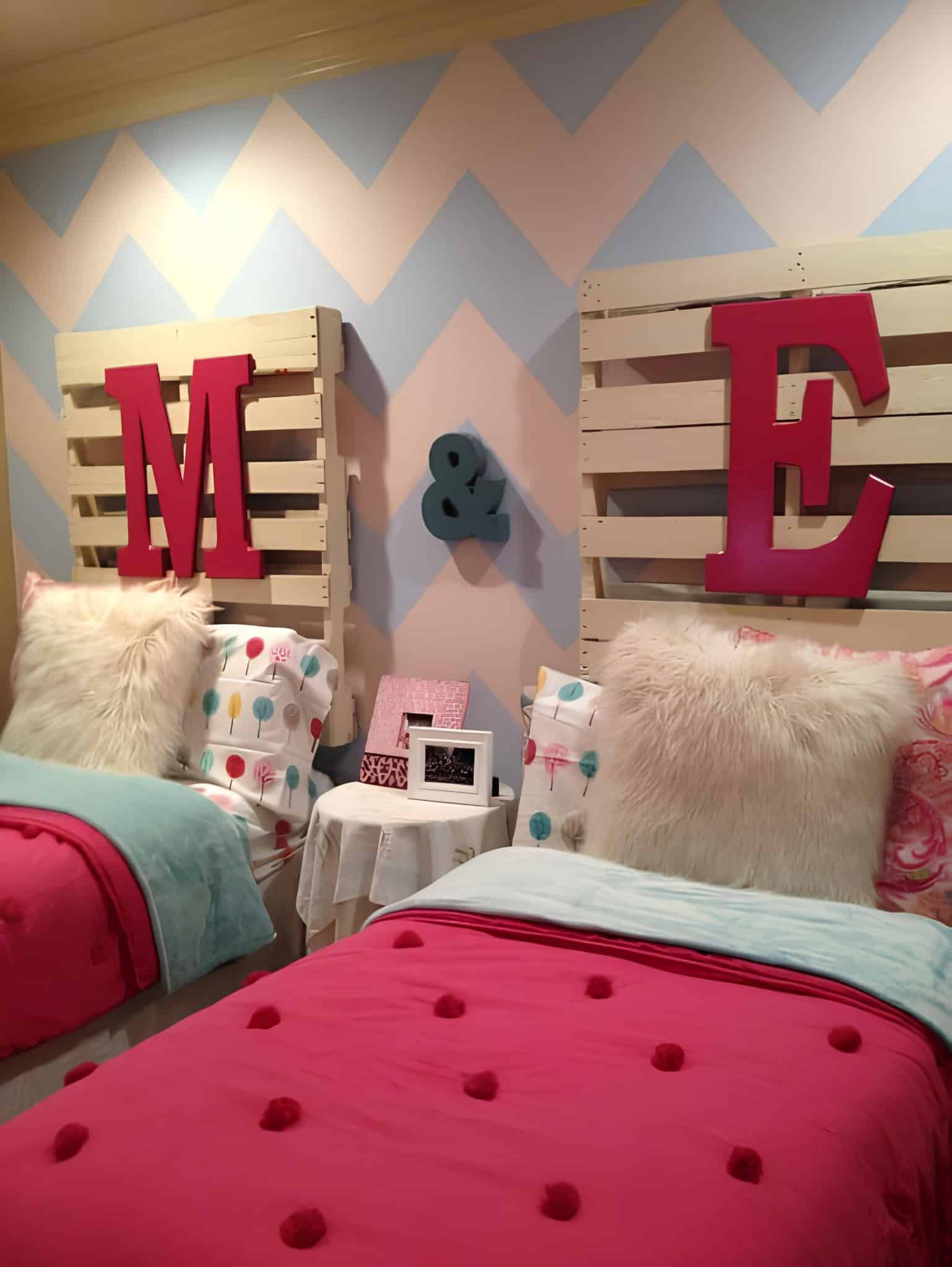 Creative kids bedroom featuring twin pallet headboards and pastel chevron wall patterns.