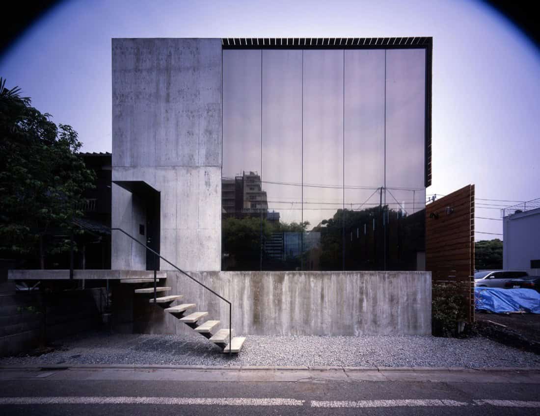 Contemporary minimalist concrete building with reflective glass facade, modern architectural design showcasing sleek lines and urban aesthetic.