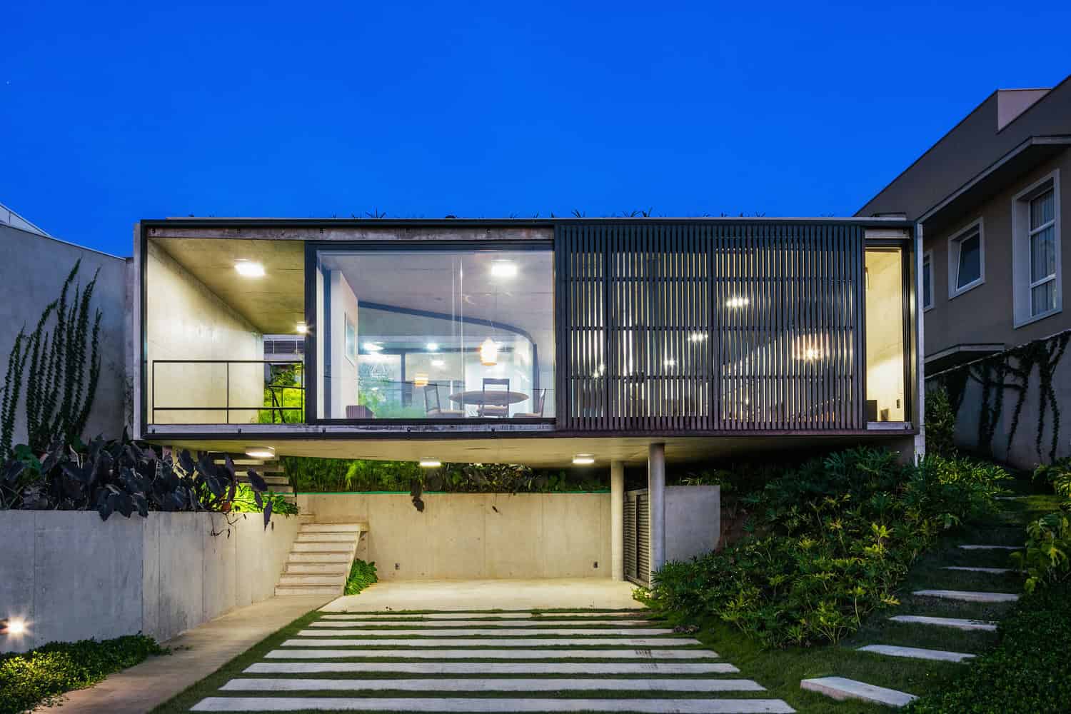 Sleek modern house with large glass windows, contemporary architectural design, and stylish outdoor landscaping at dusk. Perfect for modern home architecture and innovative exterior design.