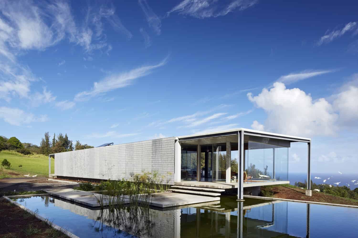 Modern minimalist house with sleek design, glass walls, and infinity pool in a scenic natural landscape, showcasing contemporary architecture and innovative design concepts.