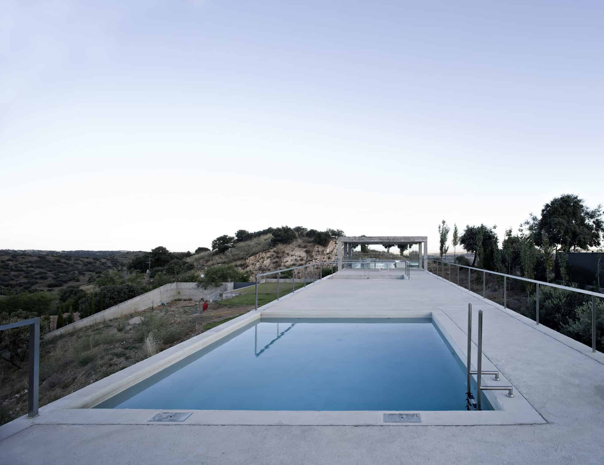 Modern minimalist infinity pool with scenic hillside views, sleek concrete deck, and contemporary design elements, ideal for luxury outdoor living and architectural elegance.