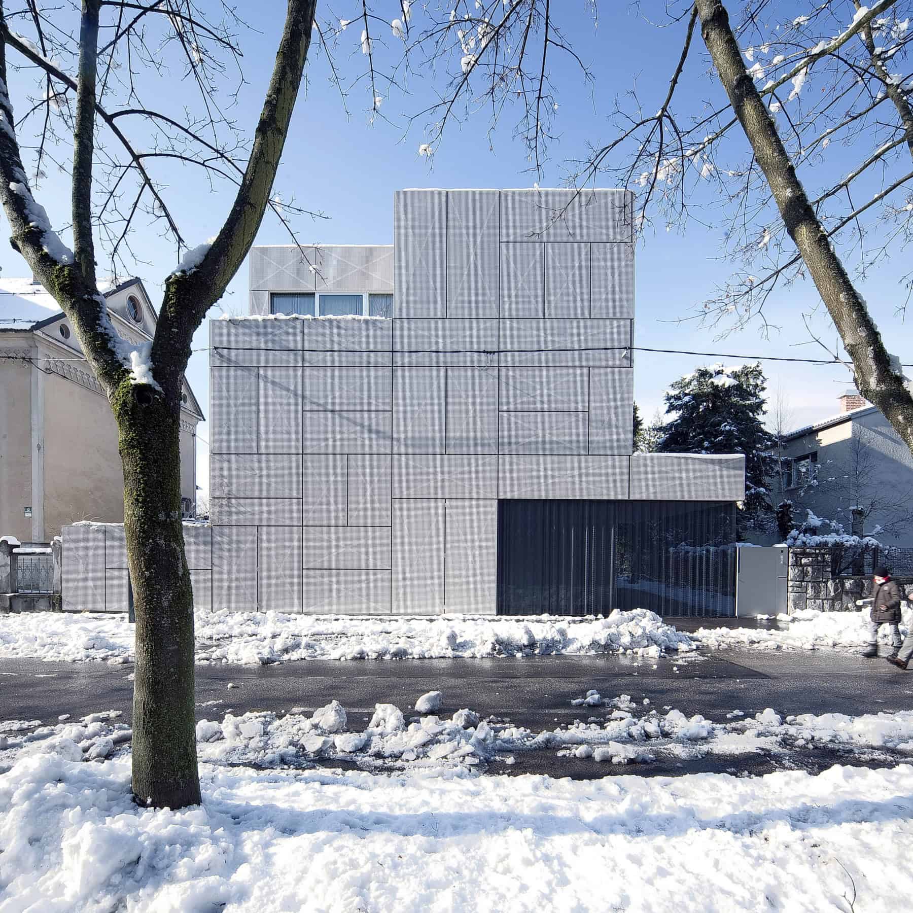 Contemporary modern house facade with geometric design, clean lines, and minimalist architecture in snowy winter setting.