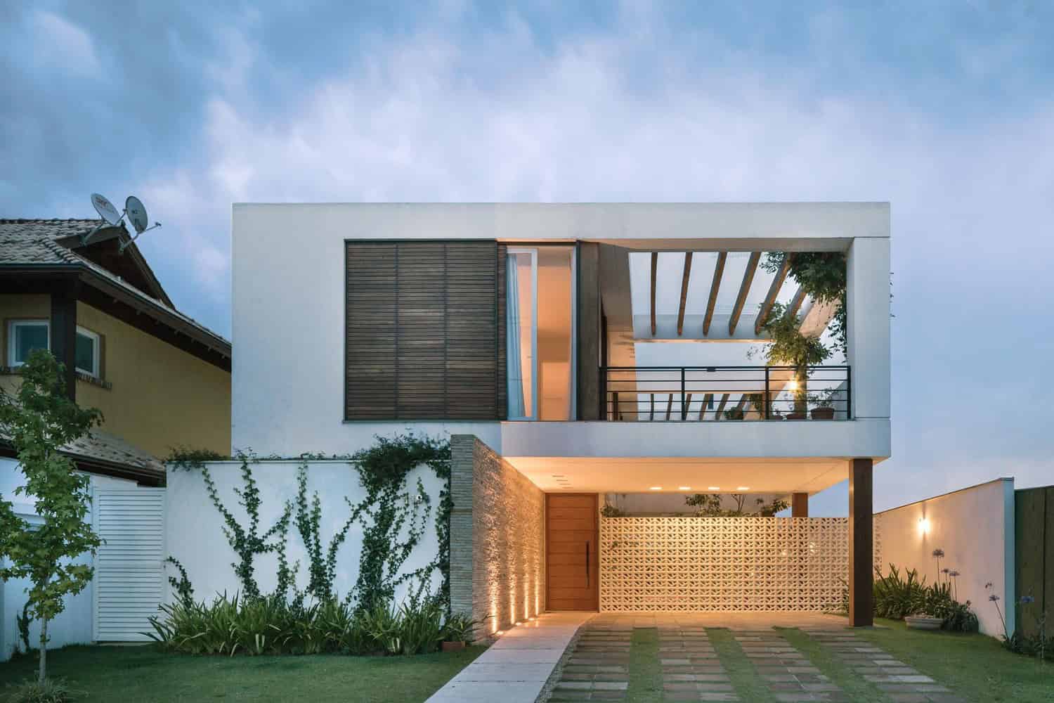 Contemporary modern two-story residential house with minimalist architecture, clean white facade, black accents, and outdoor living space with a balcony and modern landscaping.
