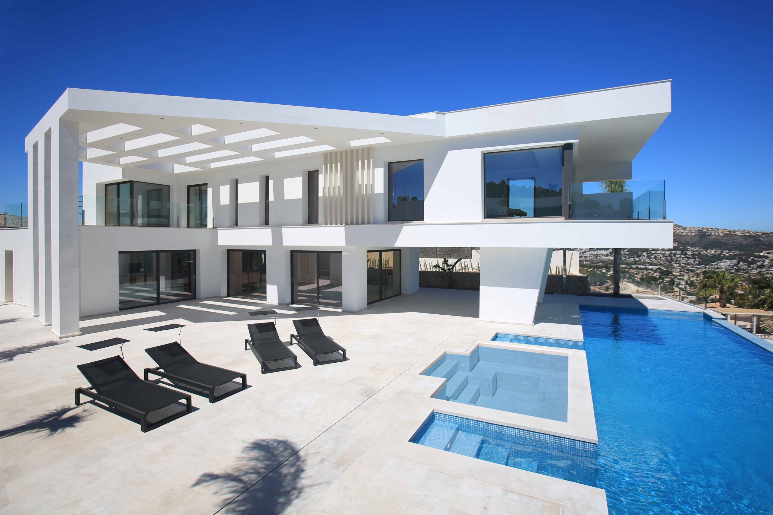 Modern white luxury villa with a sleek design, infinity pool, and spacious outdoor lounging area, showcasing contemporary architecture and innovative construction.
