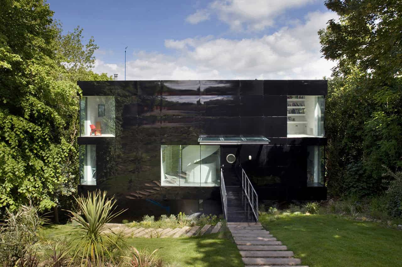 Modern black glass architecture house with sleek design and innovative facade, surrounded by lush greenery and landscaped garden for contemporary home architecture enthusiasts.