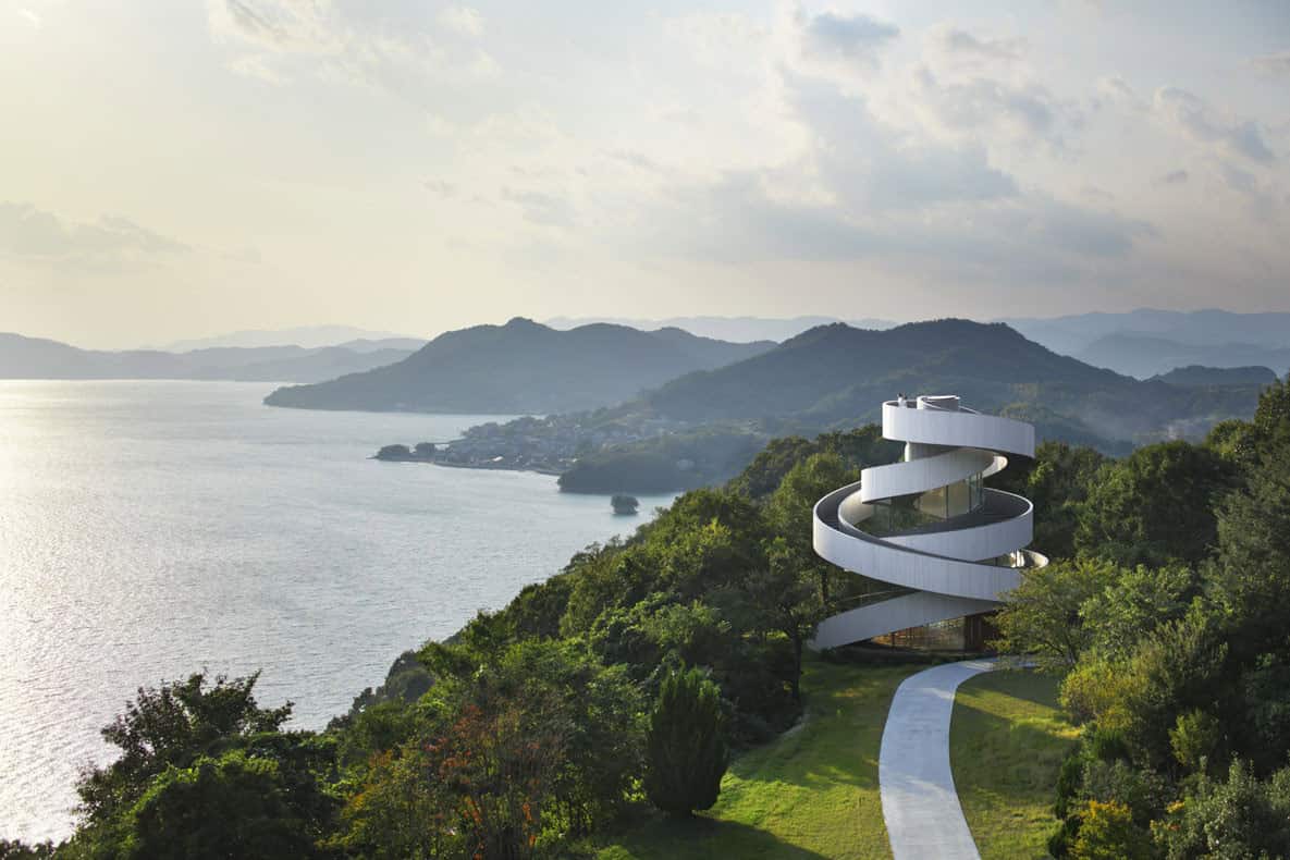 Futuristic spiral white house overlooking a scenic lake and mountain landscape, modern architectural design, innovative home architecture, hillside estate, contemporary residential architecture.